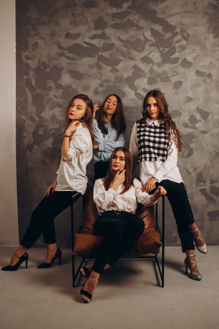 Four fashionable young women posing in a sophisticated indoor setting.